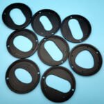 Black plastic custom machined cam plates with off-center adjustment slots for packaging machinery