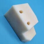 White plastic stepped positioning wear block with mounting holes for guide rails